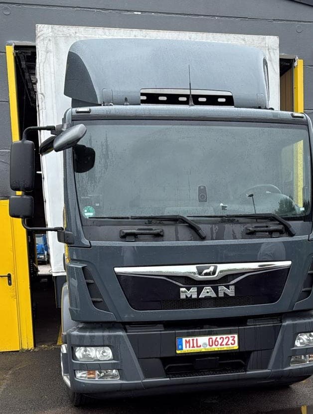 Grauer MAN-Lkw von David Transport & Logistik vor der Halle